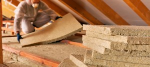 Man installing thermal insulation layer under the roof - using mineral wool panels